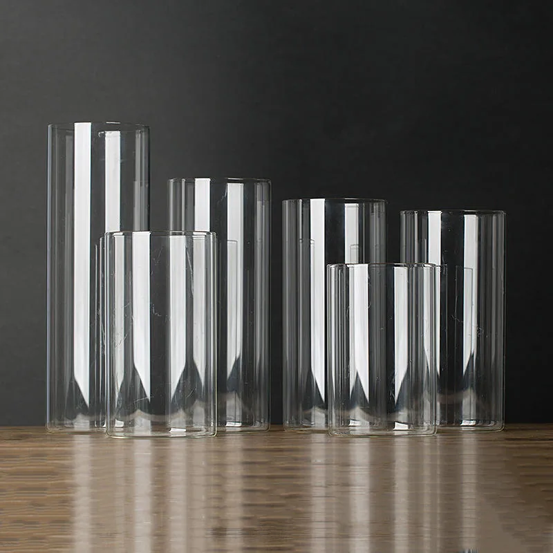 Six clear glass cylinder jars and vases in different heights on a wooden table